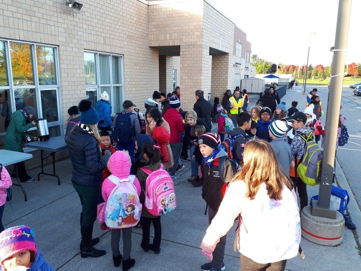 Students entering a modern school building in Cornell, Markham during morning drop-off.